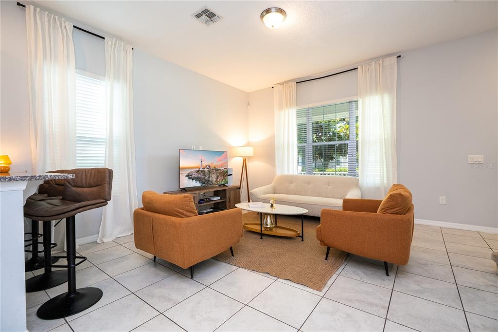 A living room features tile floors, two orange armchairs, a white sofa, and a television — 9231 GRAND ISLAND WAY, WINTER GARDEN, FL