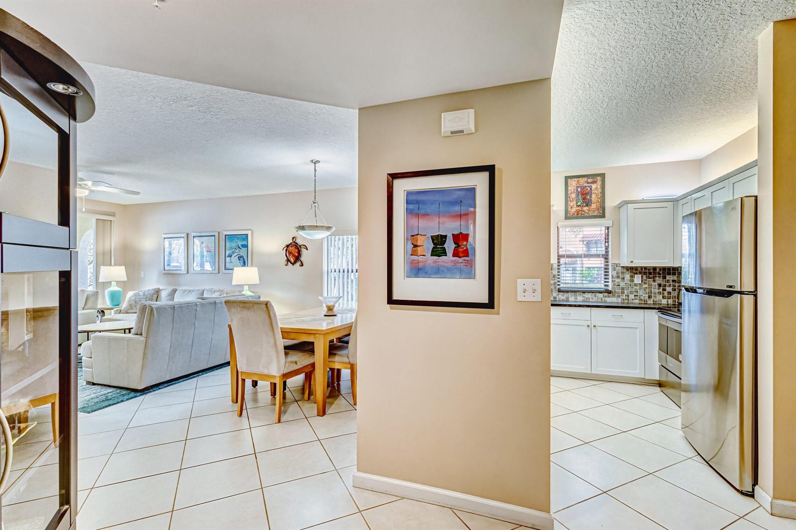 A view from a hallway looking into a dining area, living room, and kitchen — 200 Uno Lago Drive # 105, Juno Beach FL 33408, JUNO BEACH, FL