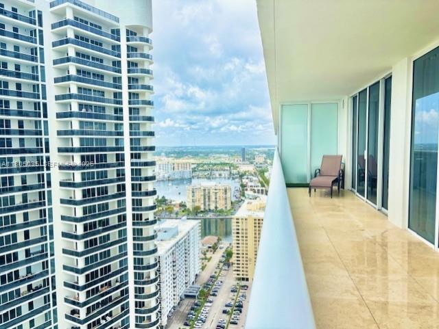 A high-rise balcony overlooks a city skyline, a body of water, and a parking lot — 1830 S Ocean Dr # 3702, Hallandale Beach FL 33009, HALLANDALE BEACH, FL