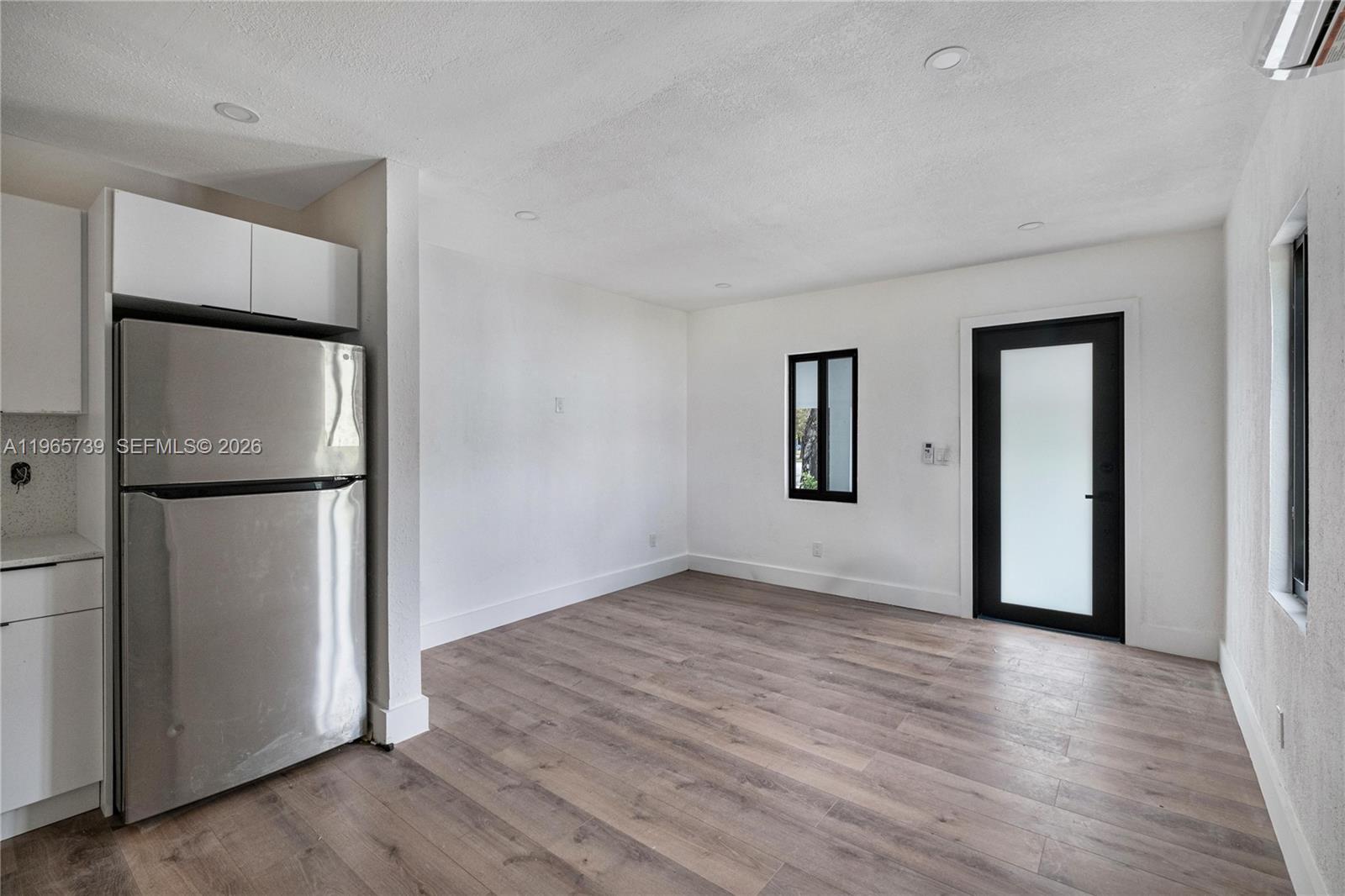 A kitchen area features a stainless steel refrigerator, white cabinets, and wood-look flooring — 6905 NW 4th Ct # B, Miami FL 33150, MIAMI, FL