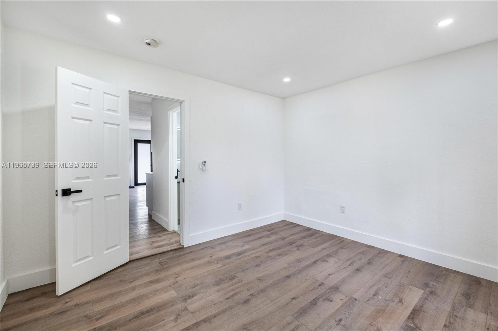An empty room features white walls, recessed lighting, and wood-look flooring with an open door — 6905 NW 4th Ct # B, Miami FL 33150, MIAMI, FL