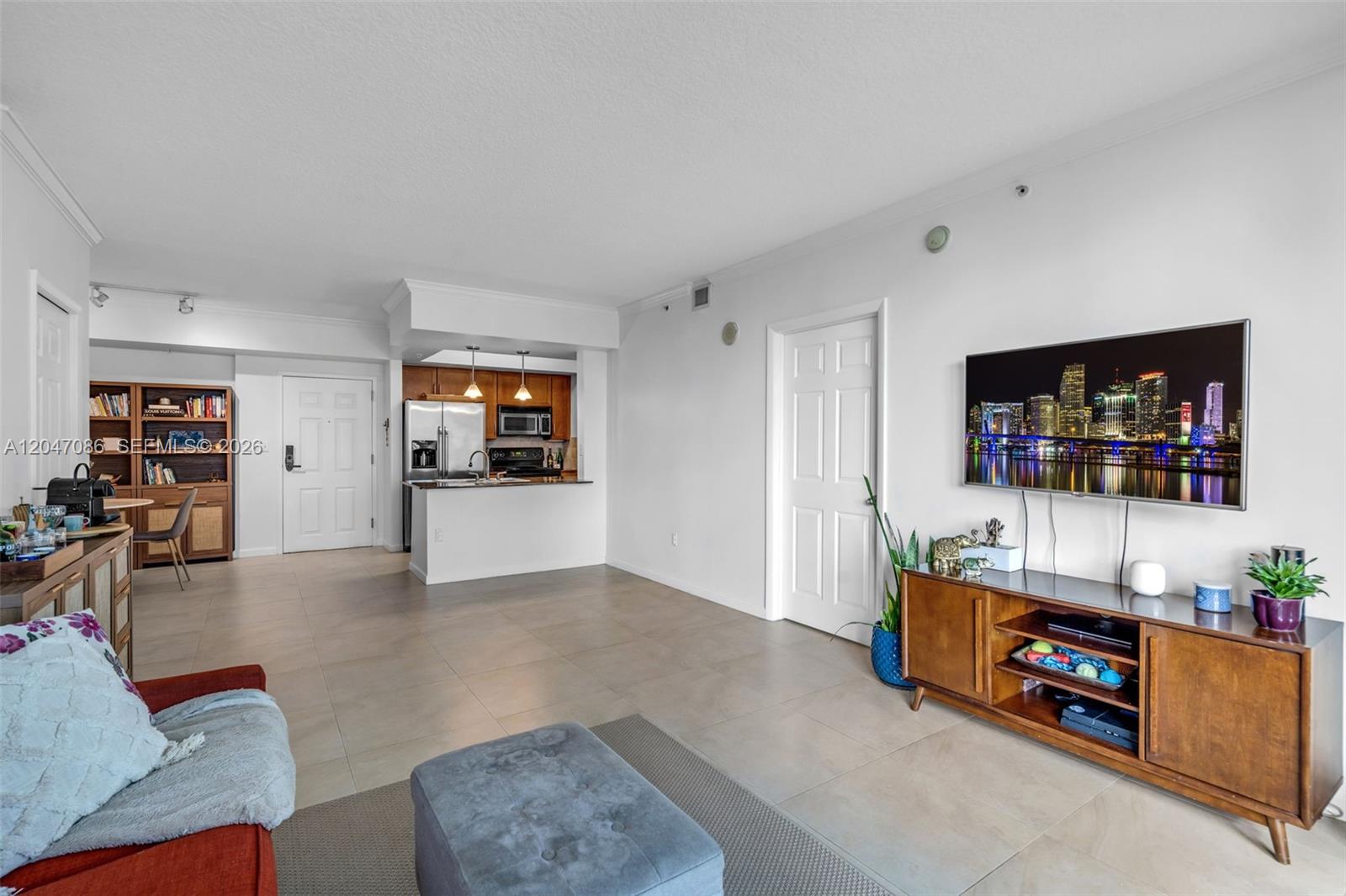 A living room with tile floors, a wall-mounted television, and an open kitchen area — 2000 N Bayshore Dr # 909, Miami FL 33137, MIAMI, FL