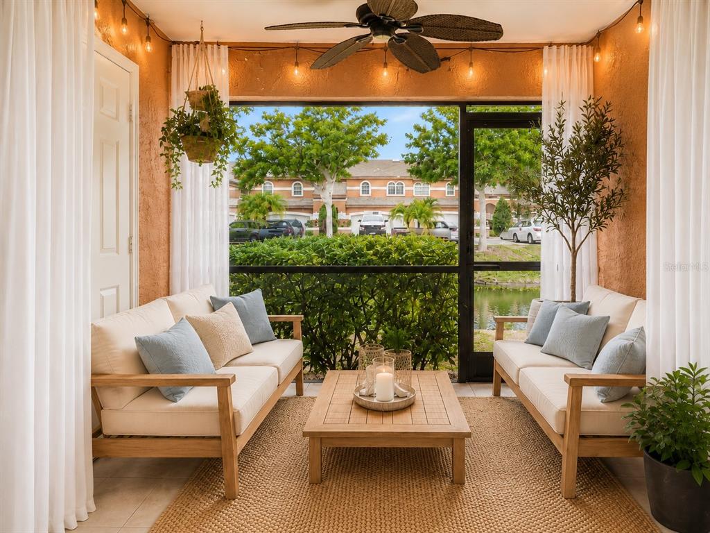 A screened-in patio features two wooden sofas, a coffee table, and views of a pond — 14623 PAR CLUB CIRCLE UNIT 14623, TAMPA, FL