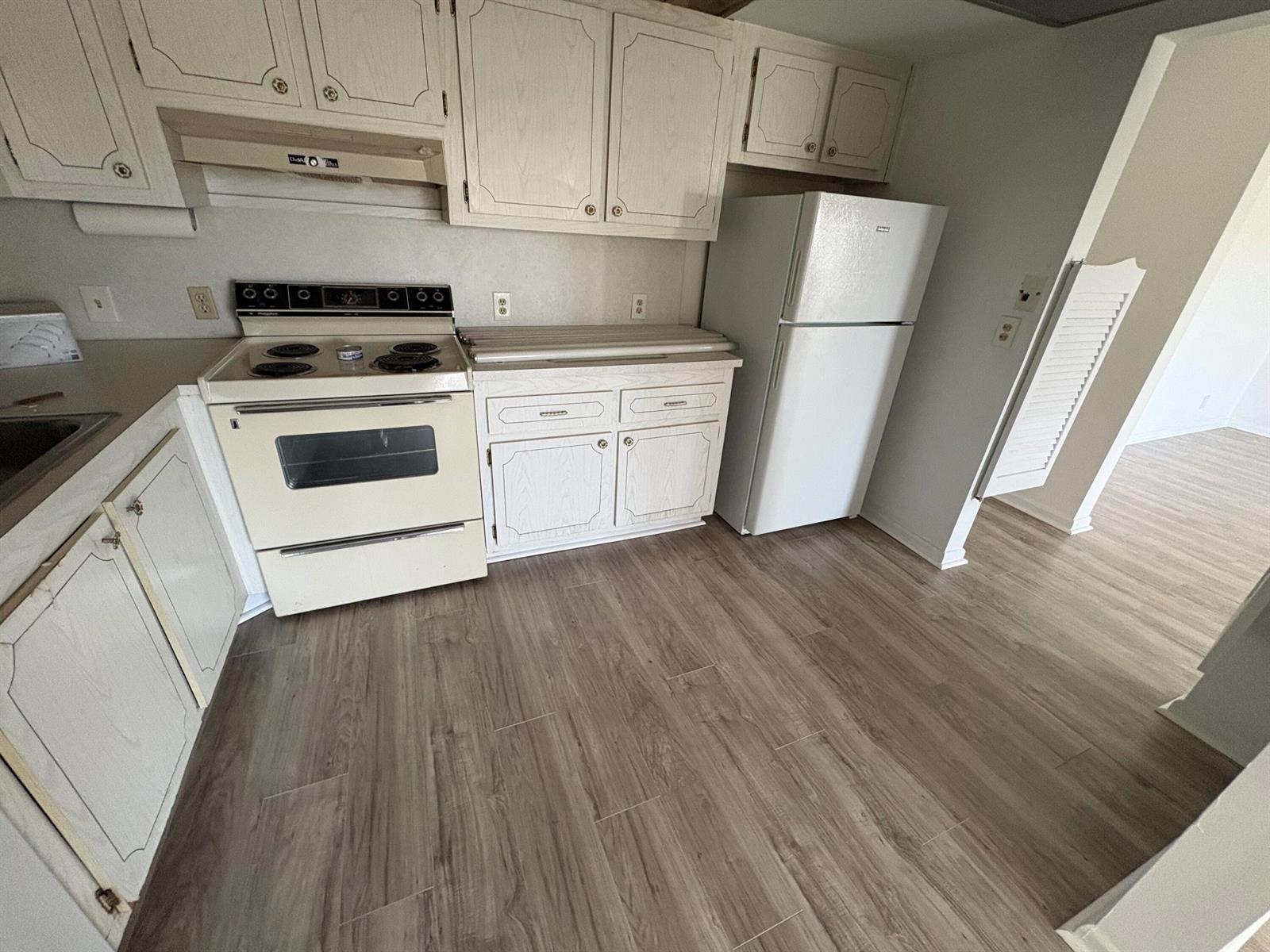 A kitchen features white cabinets, a stove, a refrigerator, and light wood-look flooring — 497 Mansfield L, Boca Raton FL 33434, BOCA RATON, FL