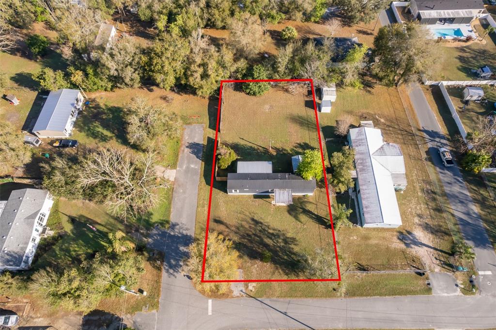 An aerial view shows a rectangular property lot outlined in red containing a mobile home — 101 CAROLINE AVENUE, LADY LAKE, FL
