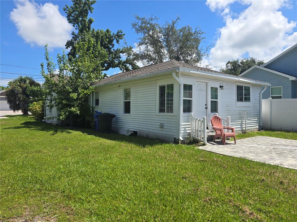 A white, single-story house with vinyl siding sits on a grassy lot with a patio — 1327 GEORGIA AVENUE, DUNEDIN, FL