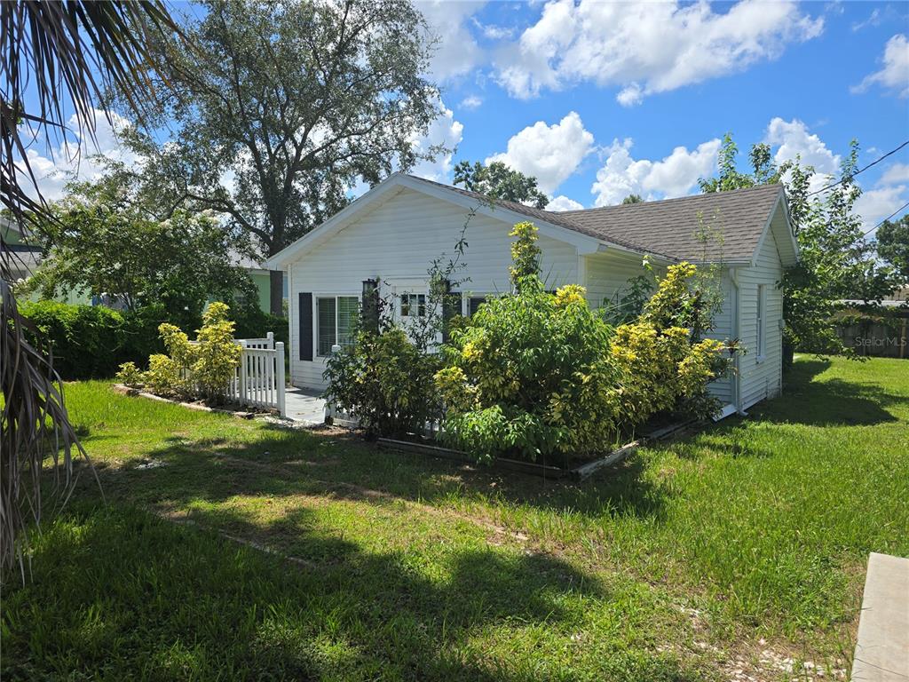A small white house with a front deck and landscaping sits on a grassy lot — 1327 GEORGIA AVENUE, DUNEDIN, FL