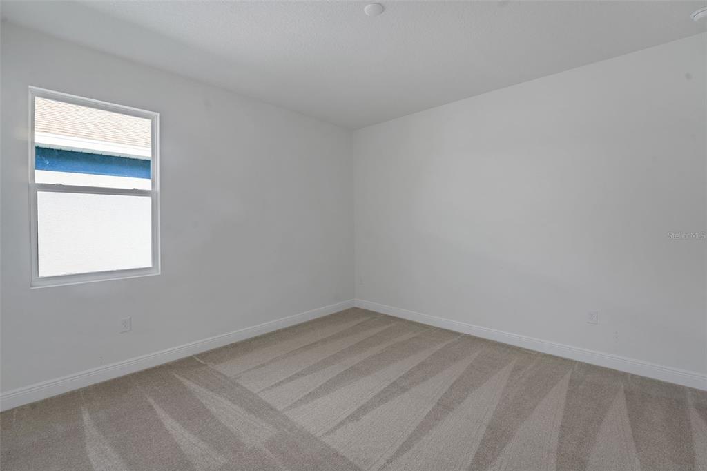 An empty bedroom features white walls, beige carpet, and a single window — 17546 VALLEYWOOD PARKWAY, LAND O LAKES, FL