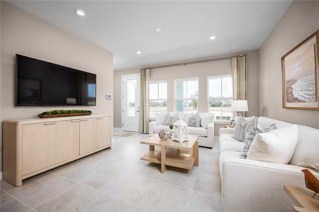 A living room features light-colored tile flooring, a large television, and a white sofa — 606 AVERYBECK LANE, DEBARY, FL