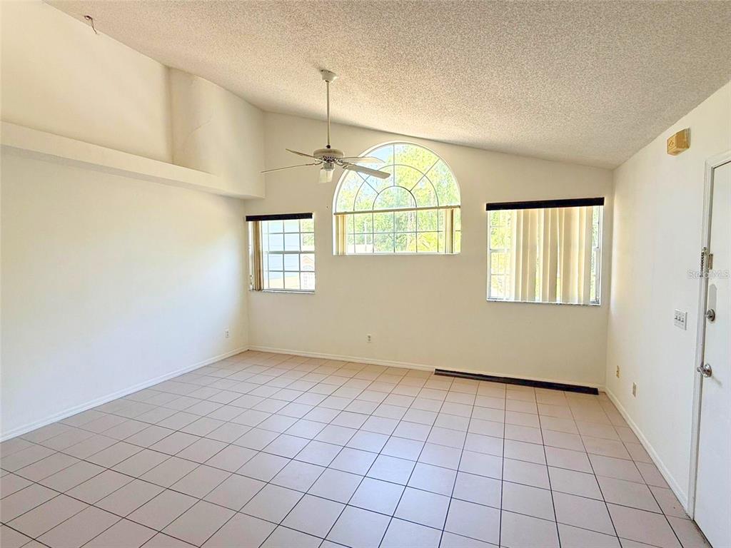 A bright living room features tile flooring, a vaulted ceiling, and an arched window — 2000 ROYAL BAY BOULEVARD UNIT 132, KISSIMMEE, FL