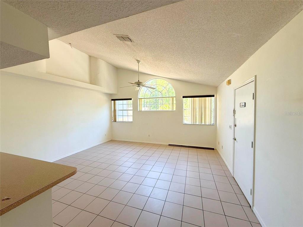 A living room features vaulted ceilings, tile flooring, a ceiling fan, and arched windows — 2000 ROYAL BAY BOULEVARD UNIT 132, KISSIMMEE, FL
