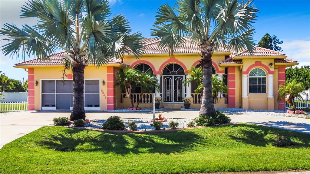 A yellow single-story house with a tiled roof, arched entryways, and two large palm trees — 18065 WING AVENUE, PORT CHARLOTTE, FL