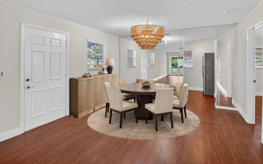 A dining room features a round table, six chairs, a chandelier, and mirrored wall panels — 801 Meadowlark Lane, Delray Beach FL 33445, DELRAY BEACH, FL