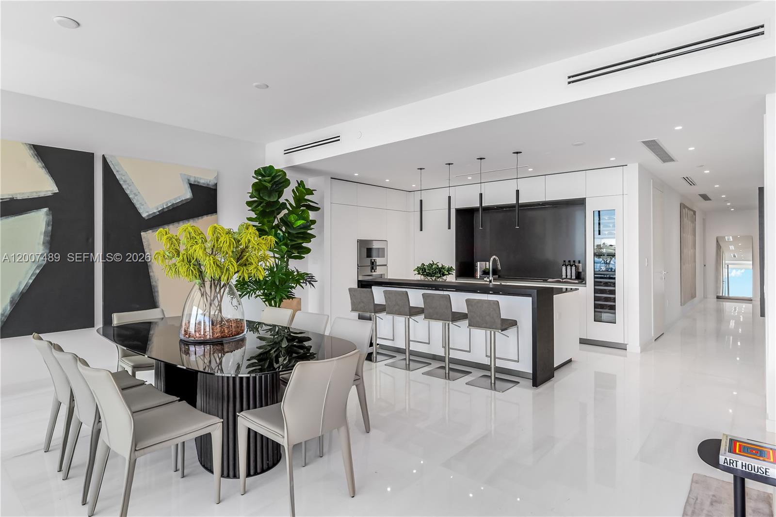 A modern dining area and kitchen feature a black island, white cabinetry, and tile flooring — 300 Biscayne Blvd Way # 2802, Miami FL 33131, MIAMI, FL
