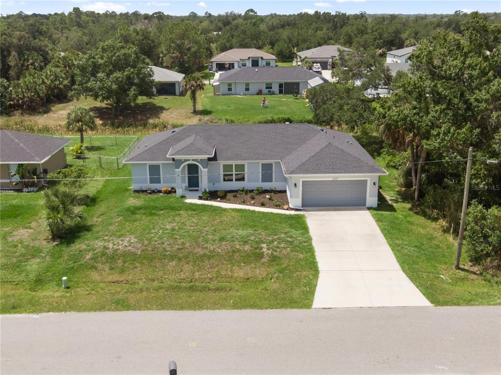An aerial view shows a single-story house with a gray roof and a concrete driveway — 3397 ZORATOA AVENUE, NORTH PORT, FL