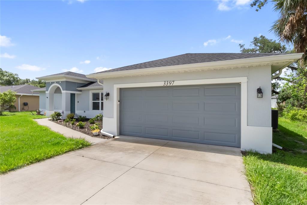 A single-story house with a gray garage door, light-colored stucco walls, and a concrete driveway — 3397 ZORATOA AVENUE, NORTH PORT, FL