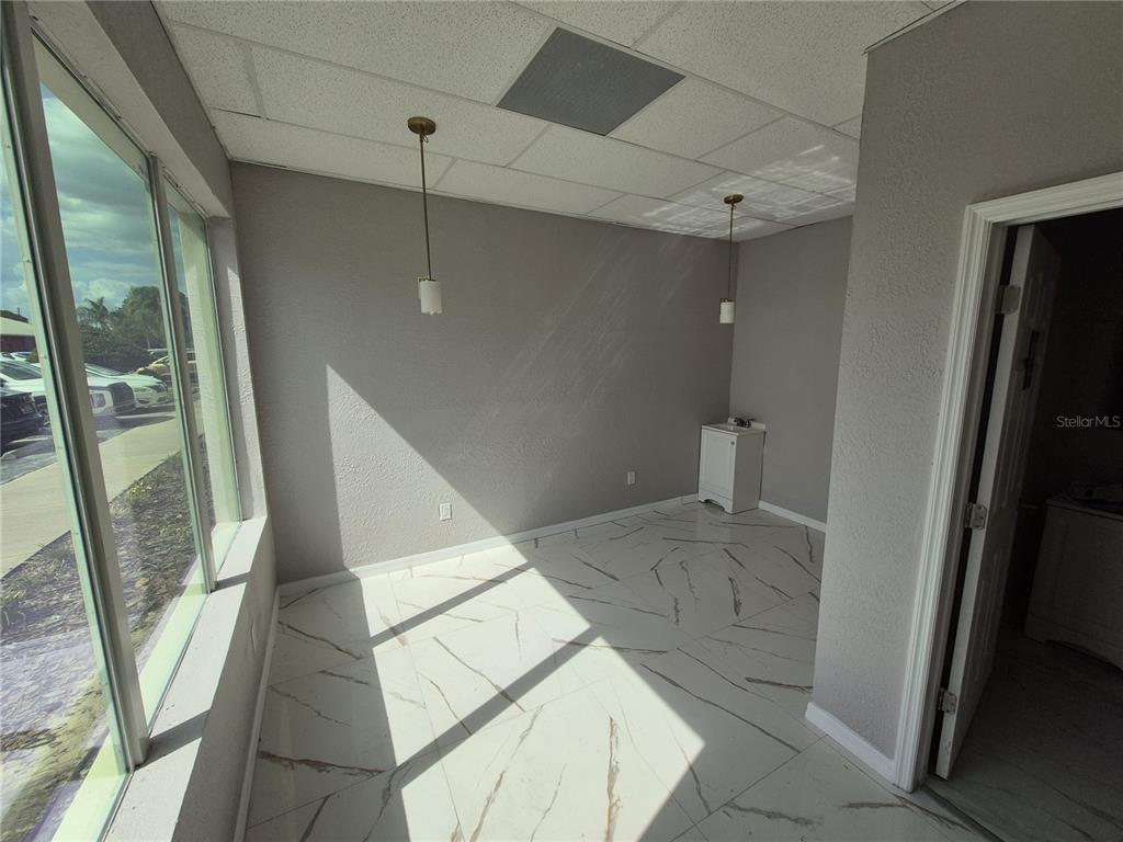 A small office space features white marble-patterned tile flooring, gray walls, and two pendant lights — 5434 LAND O LAKES BOULEVARD, LAND O LAKES, FL