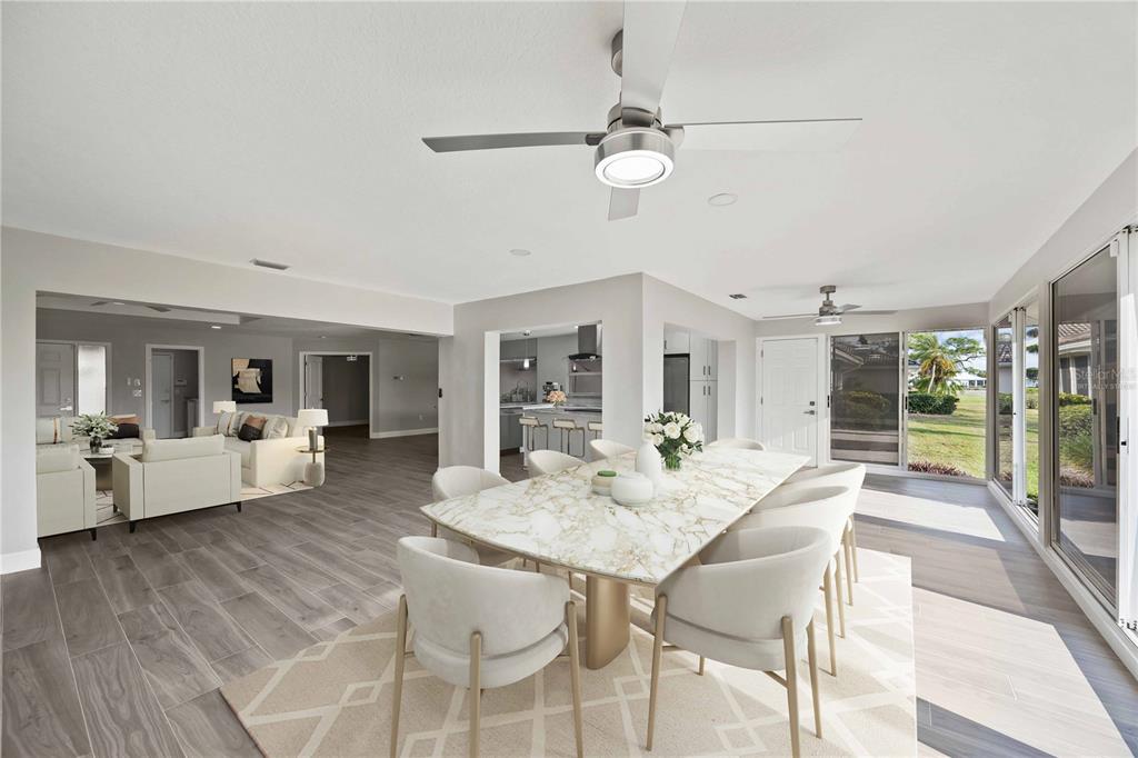 An open-concept dining area with a marble table, modern chairs, and views of the backyard — 717 CARNOUSTIE TERRACE UNIT 9, VENICE, FL