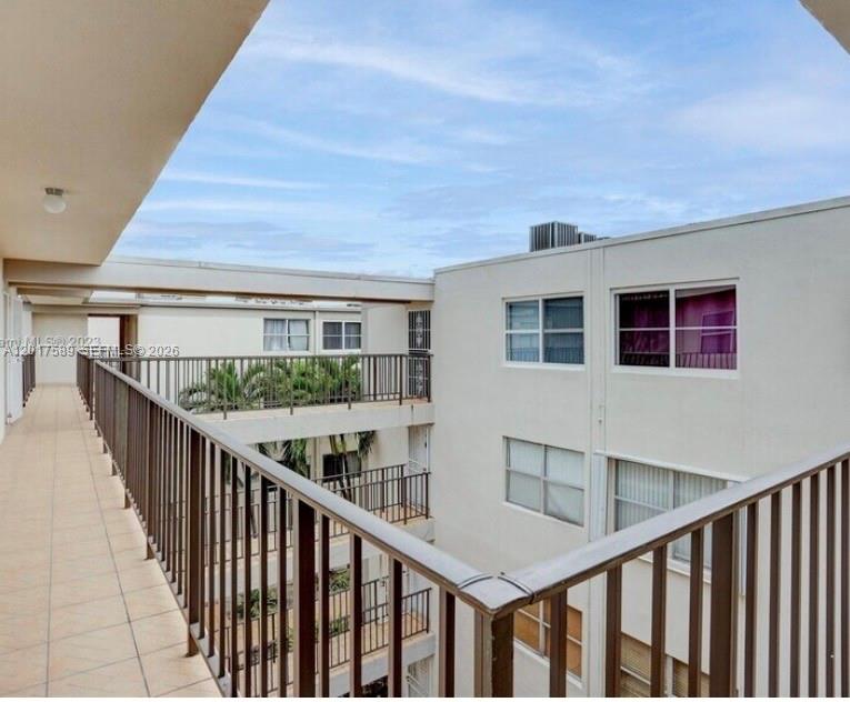 An outdoor walkway with metal railings overlooks a courtyard between two multi-story apartment buildings — 5501 NW 7th St # E412, Miami FL 33126, MIAMI, FL
