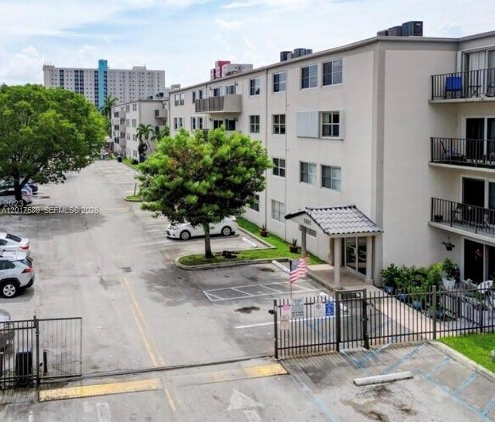 An exterior view of a multi-story apartment building with a parking lot and trees — 5501 NW 7th St # E412, Miami FL 33126, MIAMI, FL