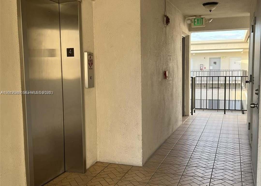 An elevator door is located in a hallway leading to an outdoor walkway — 5501 NW 7th St # E412, Miami FL 33126, MIAMI, FL
