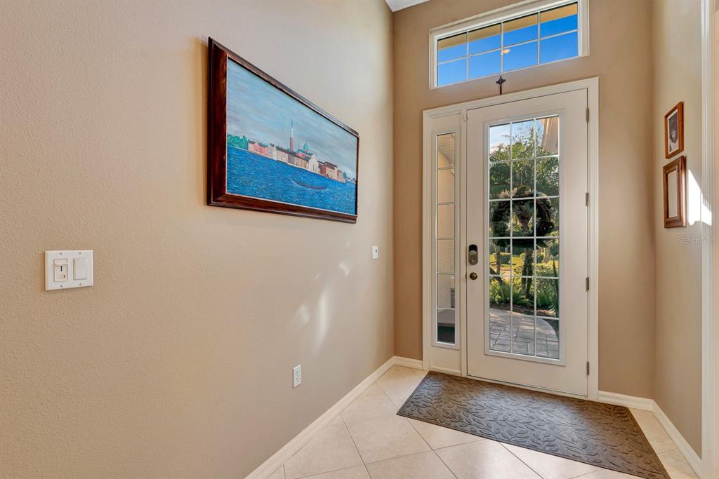 An entryway features a tiled floor, a glass-paneled front door, and a painting on the wall — 6659 PEBBLE BEACH WAY, LAKEWOOD RANCH, FL