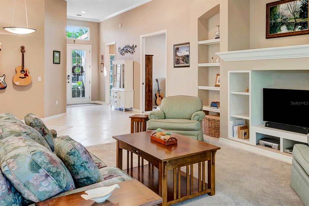 A living room features a television built-in, a coffee table, and guitars mounted on walls — 6659 PEBBLE BEACH WAY, LAKEWOOD RANCH, FL