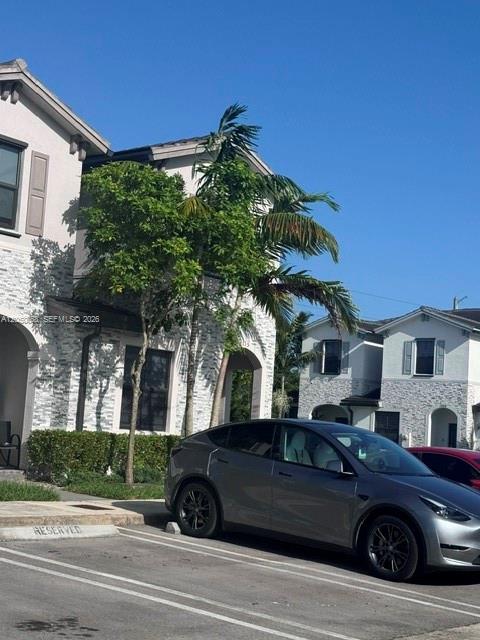 A gray Tesla is parked in front of a two-story house with stone veneer siding — 14852 SW 183rd Ter, Miami FL 33187, MIAMI, FL