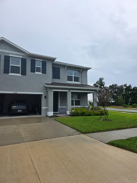 A two-story gray house with a garage, front porch, and a concrete driveway — 35518 LOCKMAN WAY, ZEPHYRHILLS, FL