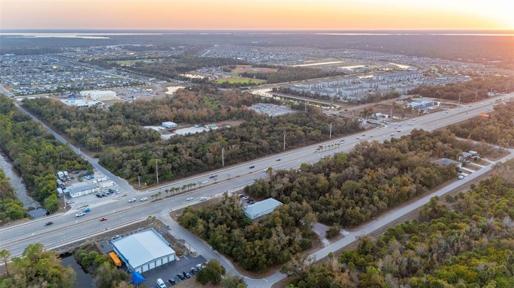 An aerial view shows a highway running through a landscape of wooded areas and buildings — 732 TAMIAMI TRAIL, PORT CHARLOTTE, FL
