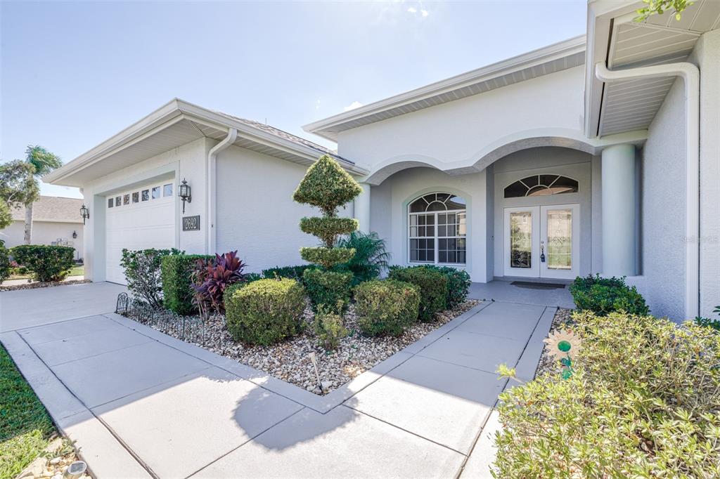 A single-story house exterior features a white stucco facade, a garage, and a landscaped walkway — 2692 HUNTINGTON HILLS DR, LAKELAND, FL