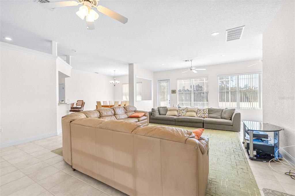 A spacious living room features a large tan sectional, a grey sofa, and tile flooring — 2692 HUNTINGTON HILLS DR, LAKELAND, FL