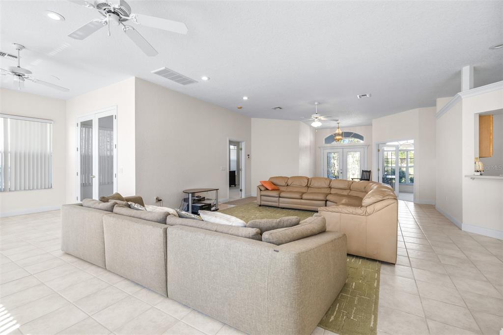 A spacious living room features light tile flooring, two large sectionals, and multiple ceiling fans — 2692 HUNTINGTON HILLS DR, LAKELAND, FL