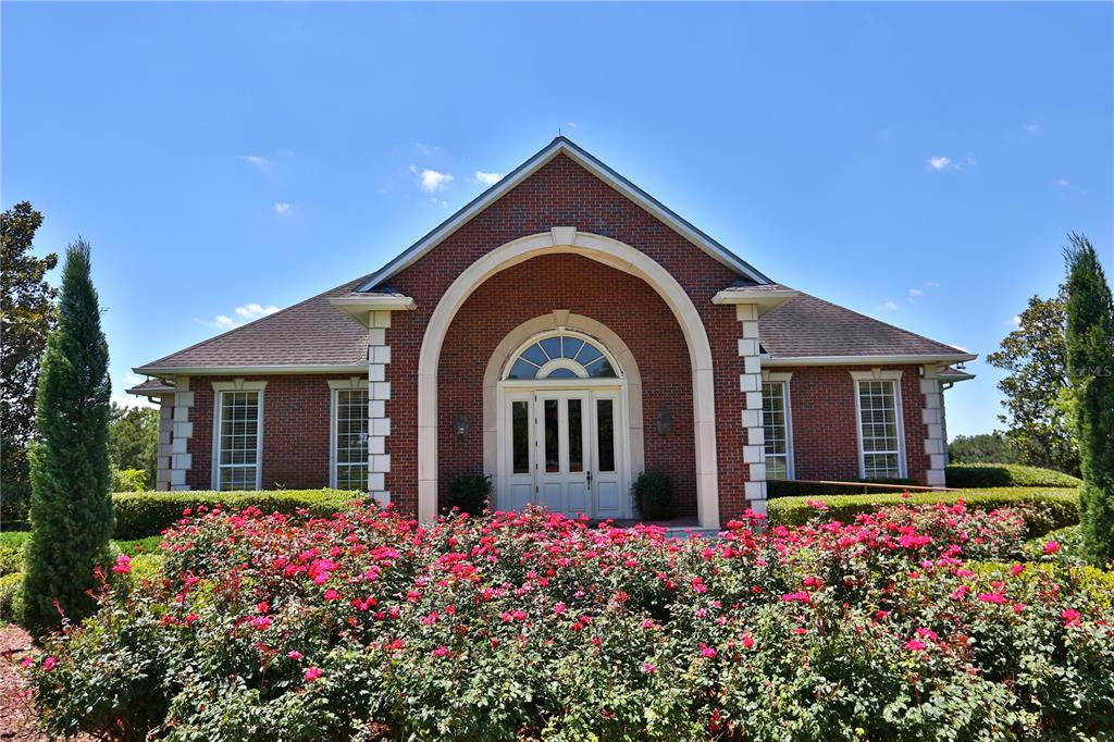 A brick house with a large arched entryway and a front garden of blooming roses — 6800 & 6500 NW 193RD STREET, MICANOPY, FL
