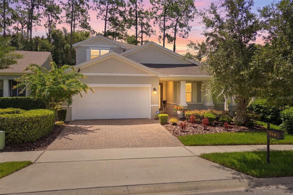 A two-story suburban house with a paved driveway, garage, and landscaped front yard at sunset — 918 S VICTORIA HILLS DRIVE, DELAND, FL