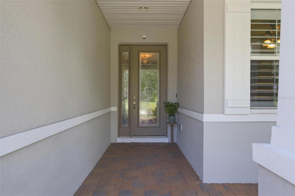 A covered entryway features a paved floor, a gray front door, and a side window — 918 S VICTORIA HILLS DRIVE, DELAND, FL