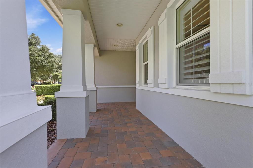 A covered front porch features paver flooring, white columns, and light gray exterior walls — 918 S VICTORIA HILLS DRIVE, DELAND, FL