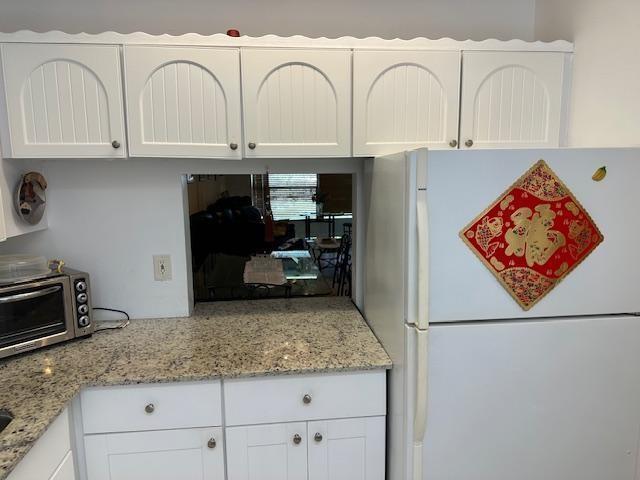 A kitchen features white cabinets, granite countertops, a toaster oven, and a refrigerator with decor — 600 NW 77th Avenue # 208, Margate FL 33063, MARGATE, FL