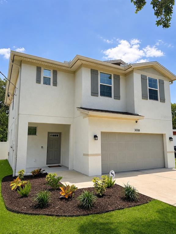A two-story house with a beige stucco exterior, a two-car garage, and a front garden — 3008 E SLIGH AVENUE, TAMPA, FL