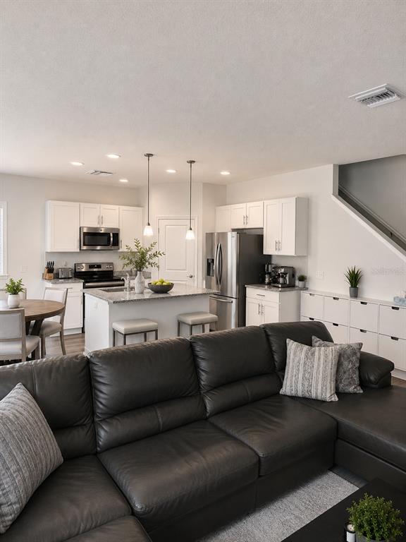 A modern open-concept kitchen with white cabinets and a central island overlooks a living area — 3008 E SLIGH AVENUE, TAMPA, FL