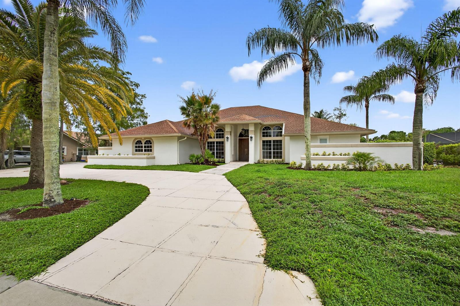 A single-story house with a brown roof, white stucco exterior, and palm trees in the yard — 1295 Longlea Terrace, Wellington FL 33414, WELLINGTON, FL