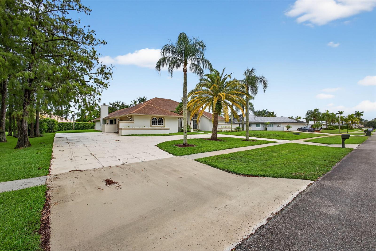 A single-story house with a large driveway, palm trees, and a green lawn — 1295 Longlea Terrace, Wellington FL 33414, WELLINGTON, FL