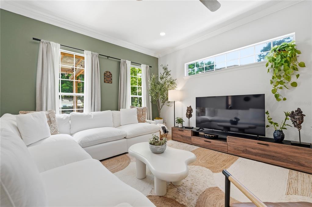 A living room features a white sectional sofa, a low wooden media console, and green walls — 336 E KALEY STREET, ORLANDO, FL