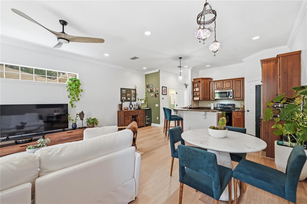 An open-concept living and dining area features a white sofa, marble table, and wooden cabinets — 336 E KALEY STREET, ORLANDO, FL
