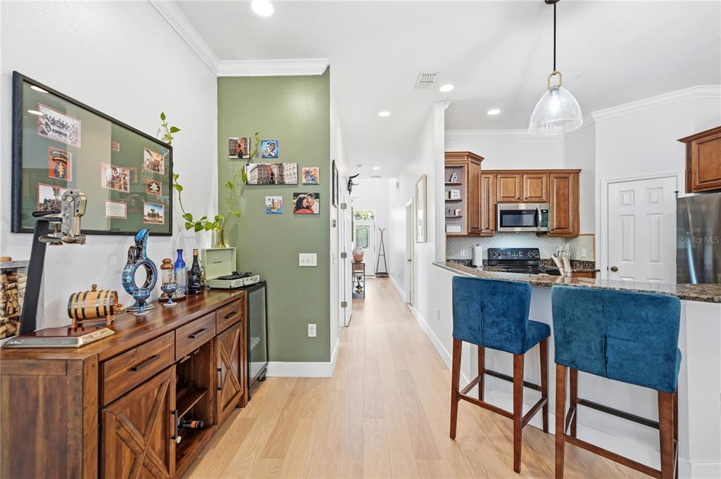 A kitchen with a breakfast bar and blue stools adjacent to a hallway and sideboard — 336 E KALEY STREET, ORLANDO, FL
