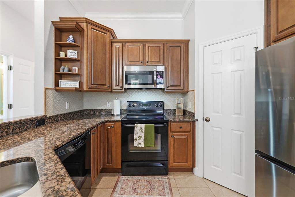 A kitchen features wood cabinets, granite countertops, a black stove, and a stainless steel microwave — 336 E KALEY STREET, ORLANDO, FL
