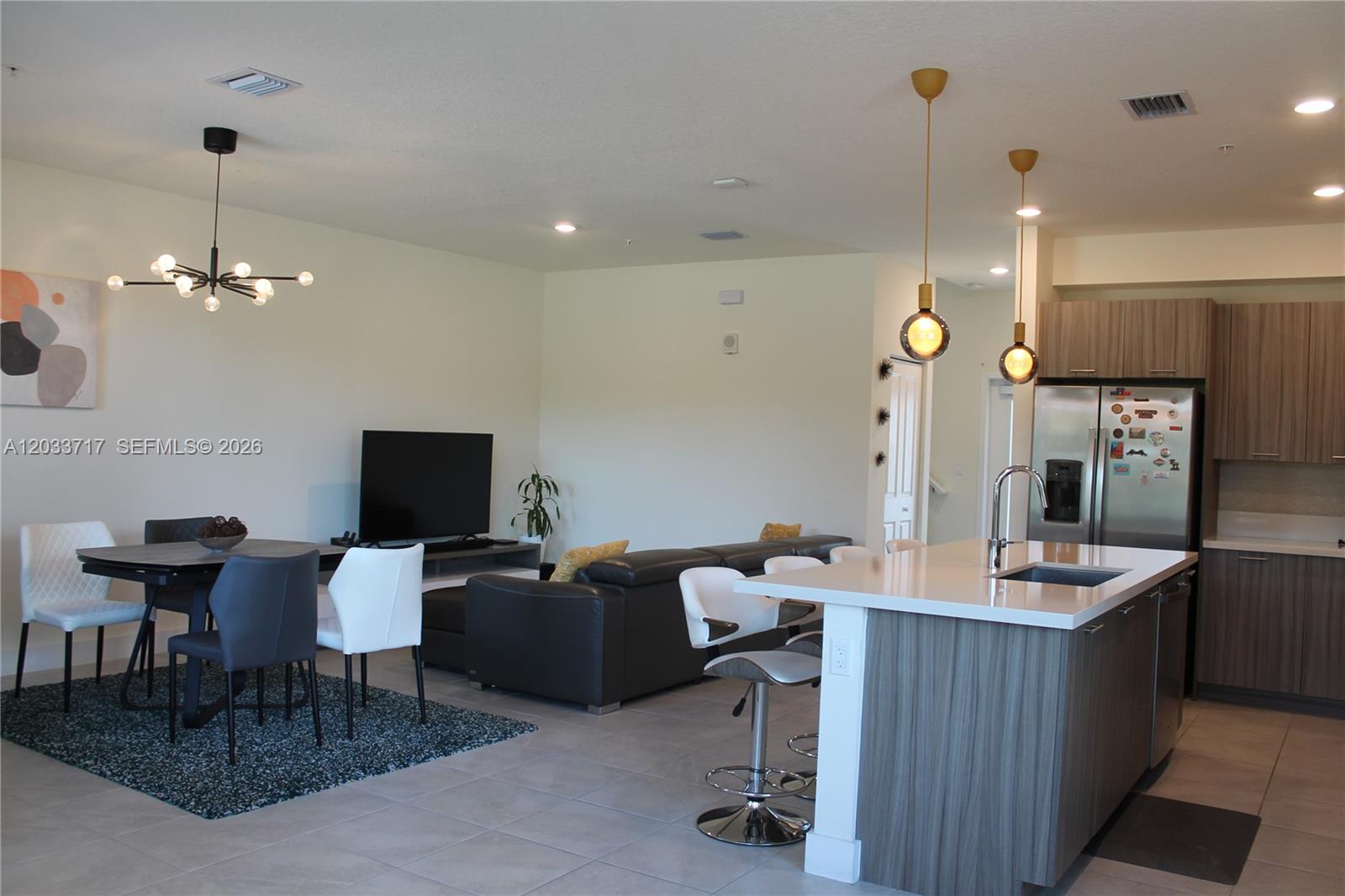 An open-concept kitchen and living area features a dining table, sectional sofa, and island — 8265 NW 41 ST # 110, Doral FL 33166, DORAL, FL