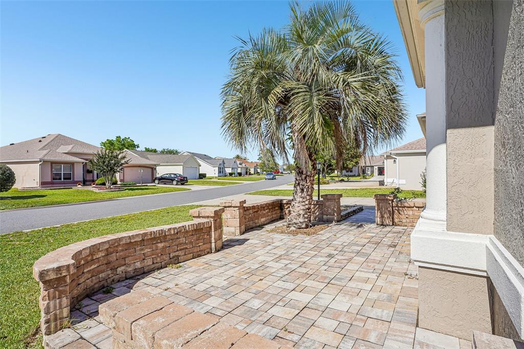 A paved patio with a low brick retaining wall and a palm tree — 2013 SANTO DOMINGO DRIVE, THE VILLAGES, FL