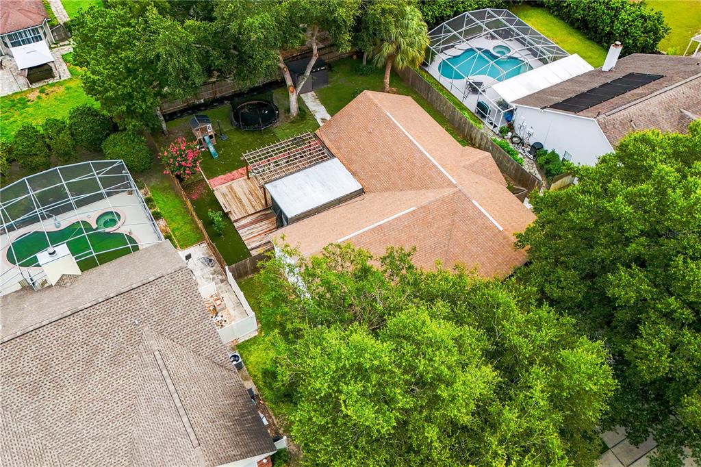 An aerial view shows a house with a shingled roof, a backyard deck, and pools — 308 SILVER PINE DRIVE, LAKE MARY, FL