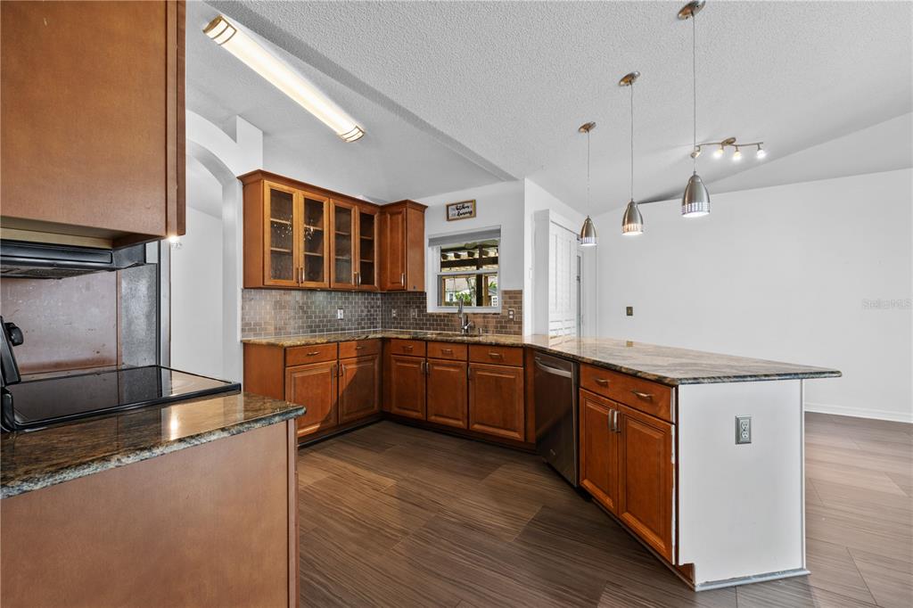 A kitchen features wood cabinets, granite countertops, a tiled backsplash, and a breakfast bar — 308 SILVER PINE DRIVE, LAKE MARY, FL